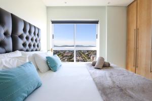 a bedroom with a large bed with a large window at Portico 1006 Beachfront Apartment with Panoramic Views in Cape Town