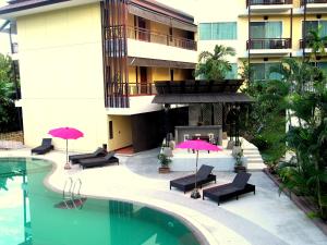 un hotel con piscina con sedie e ombrelloni di Mountain Creek Wellness Resort Chiangmai a Chiang Mai