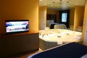 a bathroom with a sink and a tv in a room at Motel des Pentes et Suites in Saint-Sauveur-des-Monts