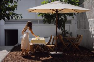 a woman in a dress cutting a cake at a table with an umbrella at Feel Porto Corporate Housing Marquês in Porto