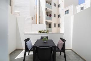 un tavolo nero e sedie su un balcone con un edificio di Modern 2BD Apartment with Maltese Balcony & Back Yard - Close to St Julian's & St Georges Bay & Sliema Promenade a Il-Gżira