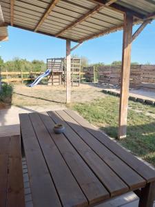 a wooden picnic table with a playground in the background at Logement cabane à la ferme in Sylvéréal