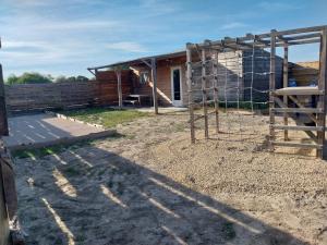 a building with a fence next to a house at Logement cabane à la ferme in Sylvéréal