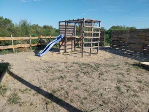 a playground with a blue slide and a wooden fence at Logement cabane à la ferme in Sylvéréal