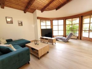 a living room with a blue couch and a tv at das.arnolds | Whirlpool | Pool | Bergblick in Berchtesgaden