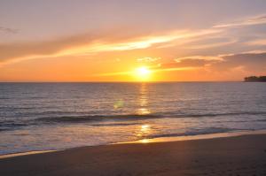 a sunset on the beach with the sun setting at Bahia Residence Cabarete in Cabarete +36 photos