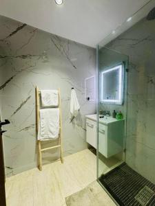a bathroom with a glass shower and a chair at LITTLE Mehdia in Mehdiya-Plage