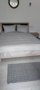 Una cama con sábanas blancas y una alfombra en el suelo en Casa M, en Câmpulung Moldovenesc