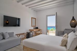 a white bedroom with a bed and a view of the ocean at Hippie Chic Hotel in Agios Ioannis Mykonos