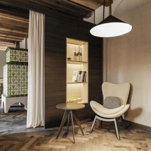 a room with a chair and a table and a shelf at Schwarzer Adler - Concept Living in Vipiteno