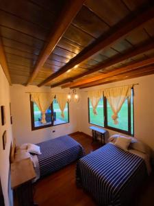 a bedroom with two beds and two windows at Paraíso selvático Casa de campo in Sucúa