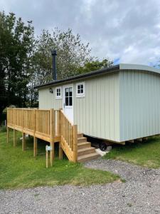 a tiny house with a porch and a deck at Rosewood Shepherds Hut in Ingleby