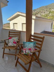 two wooden chairs sitting on a balcony with a view at Villaggio Malfidano in Buggerru