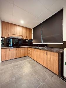 a large kitchen with wooden cabinets and a sink at New Grand Muji Style Villa at Central Penang 16pax in Bukit Lada