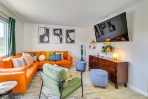 a living room with an orange couch and a table at Albuquerque Retreat with Hot Tub - Central Location! in Albuquerque