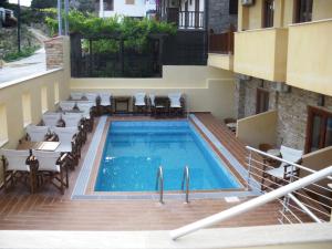 a swimming pool with tables and chairs next to a building at Ouranoupolis Princess in Ouranoupoli
