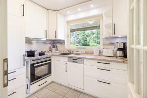 a white kitchen with white cabinets and a window at Perle am Watt in List