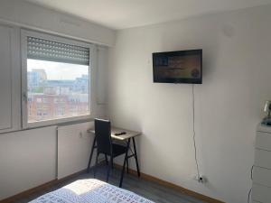 a bedroom with a desk and a television on the wall at Appartement 3 Chambres Evry plein Centre ville in Évry-les-Châteaux