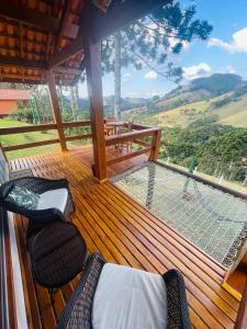 a wooden deck with two chairs and a net at Chalés Vale das Araucárias Bairro dos Onças in Gonçalves +12 photos