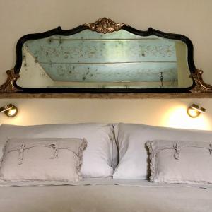 un miroir au-dessus d'un lit avec des oreillers blancs dans l'établissement Amaretto, à Tivoli
