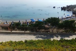 una spiaggia con ombrelloni e persone che nuotano in acqua di Olivia Budget Apartment a Paralimni