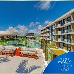 un gran edificio de apartamentos con piscina y bancos en Flat Makia Beach Experience, en Ipojuca