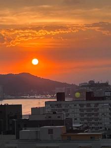 um pôr-do-sol sobre uma cidade com edifícios e a água em Estanconfor Vista Mar em Santos em Santos