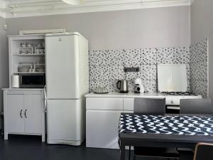 eine Küche mit einem weißen Kühlschrank und einem Tisch mit Stühlen in der Unterkunft Strawberry Forest in Jūrmala