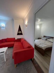 a living room with a red couch and a bed at Baudeux - Appartement simple sur Argenteuil, proche Paris in Argenteuil