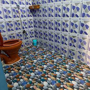 a bathroom with a tiled floor with a toilet at Blue Waves HomeStay in Pondicherry