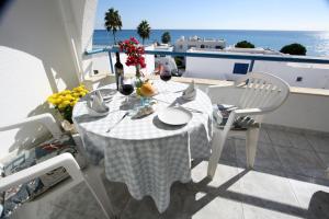 a white table and chairs on a balcony with the ocean at Pissouri Beach Apartments in Pissouri