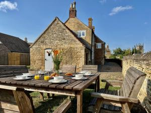 a wooden table in front of a stone house at Wothorpe House, 4 bed, Stamford Centre by Belmont Places in Lincolnshire