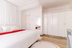 内罗毕Saruni Homes的白色卧室配有一张大床和白色橱柜