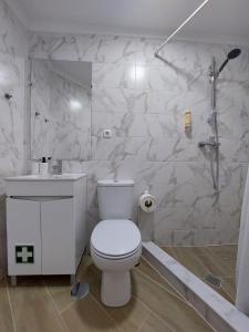 a white bathroom with a toilet and a sink at Caparica Studio - Sclusive Stay in Costa da Caparica +3 photos