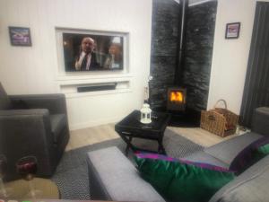 a living room with a picture of a man on the tv at The Heather Lodge in Leven