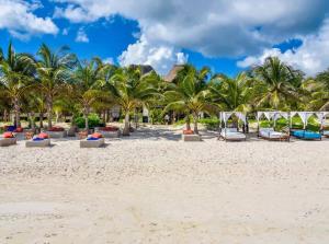 a beach with palm trees and chairs on the sand at Private Rooftop Pool - Bike to Ruins or Beach in Tulum