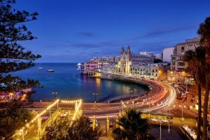 a view of a city at night at Malta Marriott Resort & Spa in St. Julianʼs