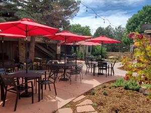 a group of tables and chairs with red umbrellas at Hilltop Inn Broomfield Denver in Broomfield