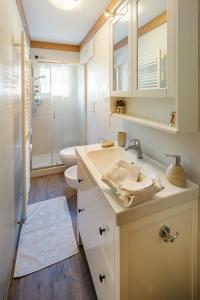 uma casa de banho branca com um lavatório e um WC em CiasaToa em Cortina dʼAmpezzo