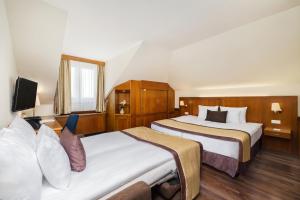 a hotel room with two beds and a tv at Carlton Hotel Buda Castle in Budapest