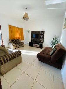 a living room with two couches and a flat screen tv at Chácara Vovô Juca Pouso Alegre in Pouso Alegre