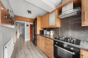 a kitchen with wooden cabinets and black appliances at Luxury 3-BR Home-Driveway, Sky-TV-Fast WiFi in Meanwood
