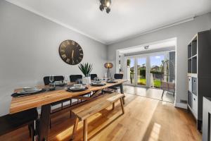 a dining room with a table and a clock on the wall at Luxury 3-BR Home-Driveway, Sky-TV-Fast WiFi in Meanwood +31 photos