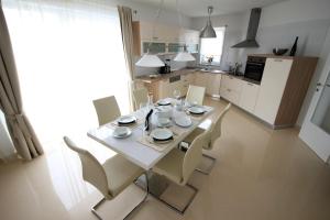 kuchnia z białym stołem i krzesłami w pokoju w obiekcie Apartments Villa Mantinela w mieście Malinska