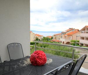 a black table with a red flower on a balcony at Apartments Villa Mantinela in Malinska