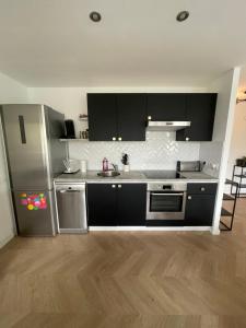 a kitchen with black cabinets and a stainless steel refrigerator at Appartement calme à Anglet in Anglet