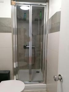 a shower with a glass door in a bathroom at King's Cross Road Private Rooms in London