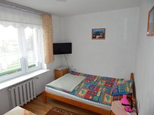 niewielka sypialnia z łóżkiem i oknem w obiekcie APARTAMENT i pokoje Aura Dom Wczasowy w Darłówku