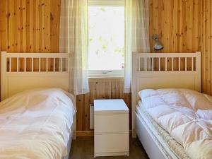 two beds in a bedroom with wooden walls and a window at 4 person holiday home in BENGTSFORS in Bengtsfors