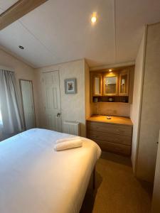 Un dormitorio con una cama blanca y un lavabo. en 56 Main Park Caravan Hire Lillardsedge Holiday Park Jedburgh, en Jedburgh